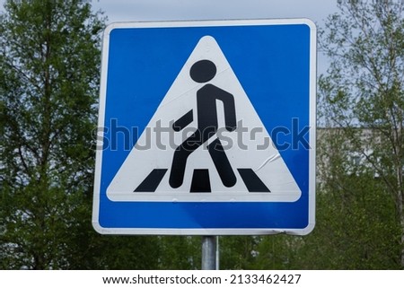 Road sign pedestrian crossing. Zebra crossing, pedestrian cross warning traffic sign in blue and pole Royalty-Free Stock Photo #2133462427