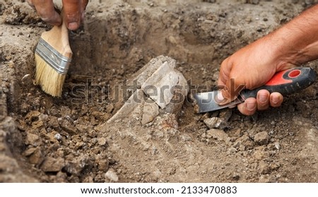 Archaeological excavations, archaeologists work, dig up an ancient clay artifact with special tools in soil Royalty-Free Stock Photo #2133470883