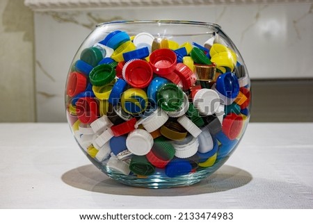 a lot of plastic bottle caps, healthy food concept, unhealthy food. plastic lids on the table, lids in a bowl.
