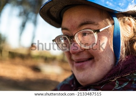 Outdoor portrait of a 39 year old white woman with the Down Syndrome, smiling and wearing a bike helmet
