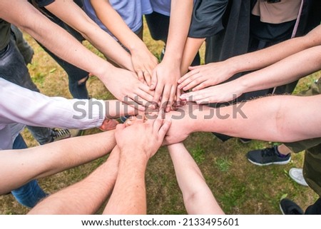 People (men and women) stretch their hands to each other, symbolizing team, teamwork, friendship, team building