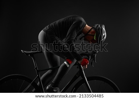 male cyclist riding road bicycle on black background Royalty-Free Stock Photo #2133504485