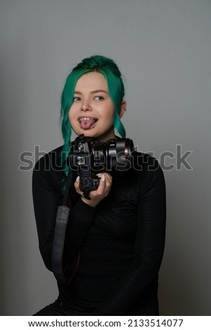 Girl photographer with green hair in black clothes holds a camera in her hands. creative young woman.