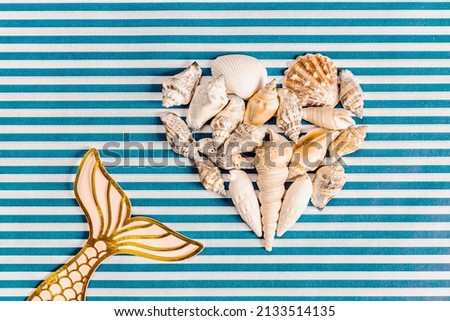 seashells forming a heart, paper ice cream and toy pineapple on white and blue background