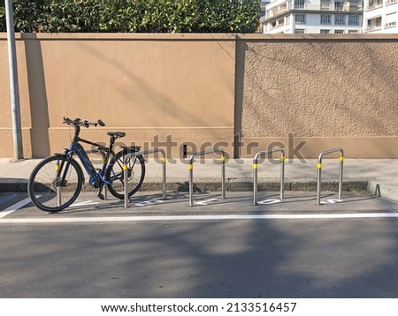 Parking for bikes on the street with a wall of a building behind. Bike parked in front of a wall.  