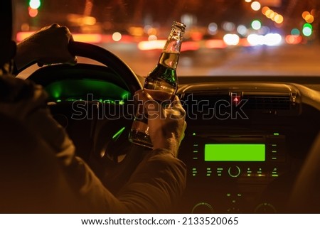 Drinking beer while driving car. Man hold bottle alcohol in hand at the night. Royalty-Free Stock Photo #2133520065