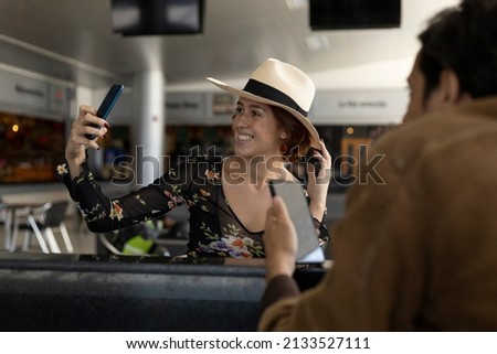 Young Latin American girl (22) with cowboy hat is on vacation and takes a self-portrait with her cell phone. Concept of technology and vacation