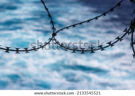 Close up view of razor wire fortification at ship's stern. Anti piracy protection. HRA, High Risk Areas. Illegal boarding. Ship's wake in background. Selective focus.