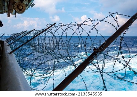 Ship's stern fortified with razor wire. Anti piracy protection is mounted before entering (HRA) Piracy High Risk Areas to prevent illegal boarding. Royalty-Free Stock Photo #2133545535
