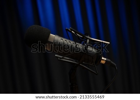 Black vocal microphone is stand in sound recording studio room using for podcast production radio or lead singer instrument meaning perform music audio wave analog or digital signal wavelength media.