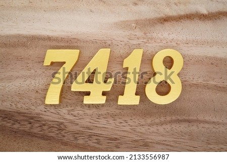 Wooden  numerals 7418 painted in gold on a dark brown and white patterned plank background.