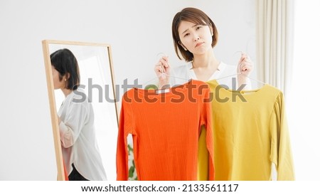 Young woman in front of a mirror choosing clothes Fashion image
