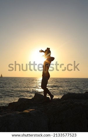 Silhouette of a woman and man dancing against a sea background
