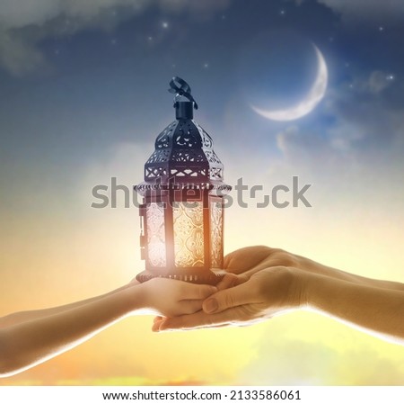 Ornamental Arabic lantern with burning candle glowing in hand. Festive greeting card, invitation for Muslim holy month Ramadan Kareem. Royalty-Free Stock Photo #2133586061