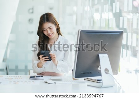 Focused asian business woman working studying online in office looking at laptop making notes, serious asian woman employee or student watching webinar writing information in notebook sitting at desk.