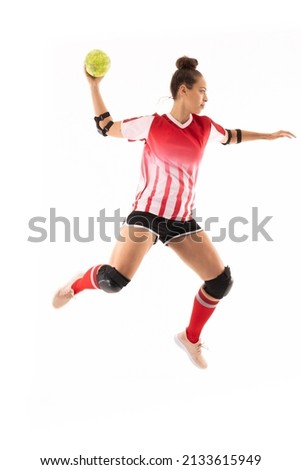 Full length of biracial young female handball player in mid-air playing against white background. unaltered, copy space, sport, sports uniform, safety, athlete and team handball. Royalty-Free Stock Photo #2133615949