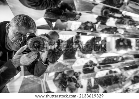 Photographer surrounded by mirrors. Reflection of man everywhere