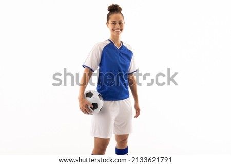 Portrait of smiling biracial young female soccer player with ball standing against white background. unaltered, sport, sports uniform, copy space, athlete and women's soccer. Royalty-Free Stock Photo #2133621791