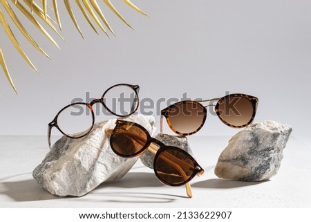 Sunglasses and glasses sale concept. Trendy sunglasses on gray background with golden palm leaves. Trendy Fashion summer accessories. Copy space for text. Summer sale. Optic store discount poster Royalty-Free Stock Photo #2133622907