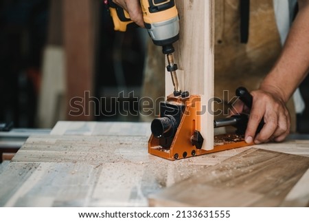 carpenter use drill bit and centering dowel jig or pocket hole jig tool to make strong joints on wooden plate. woodworking concept.selective focus. Royalty-Free Stock Photo #2133631555