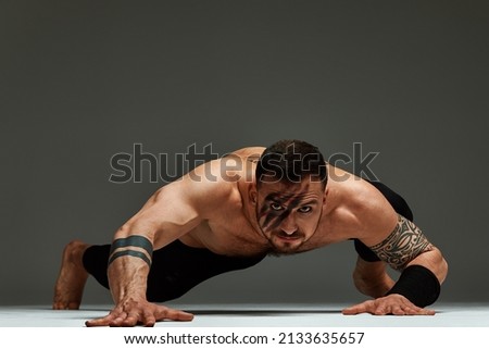 Animal instinct fitness instructor sportsman showing his incredible flexibility with an animal flow move in studio against a gray background Royalty-Free Stock Photo #2133635657