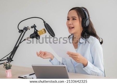 Beautiful asian young woman radio host working, setting microphone, preparing to speak before recording podcast and live on social media. Technology of on-air online in broadcasting at home studio.