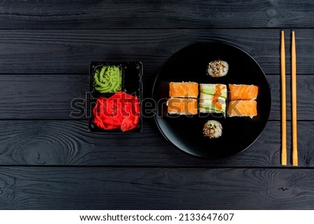 Delicious sushi on a black plate, lie on a black wooden board.