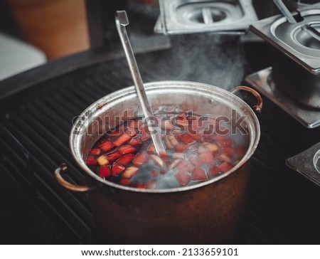 Spicy hot homemade mulled wine boiling in a pot on grill in kitchen.