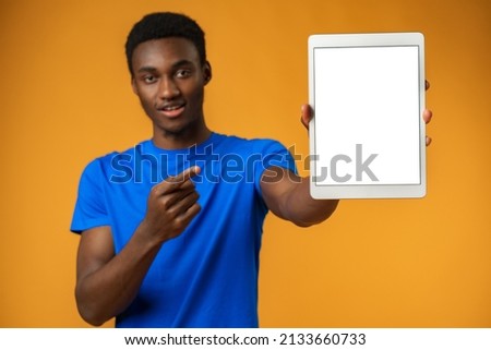 African american man showing blank digital tablet screen with copy space in yellow studio.