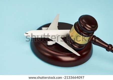 Aviation law concept. Judge gavel and airplane on blue background. Flight cancellation Royalty-Free Stock Photo #2133664097