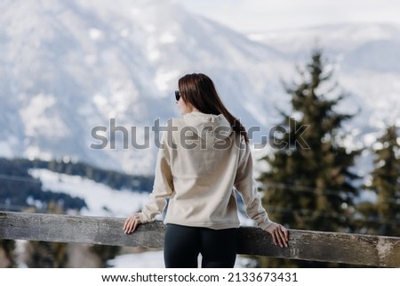  A woman looks at the snow-capped mountains on the observation deck of the tower. High quality photo