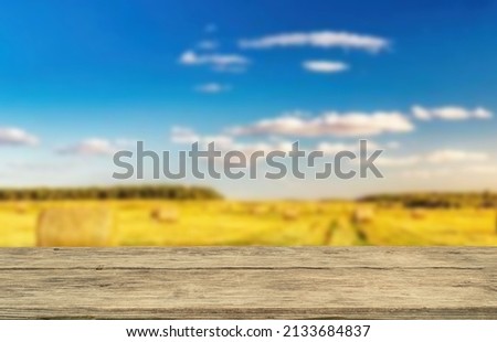 Wooden table top on blur rice field background in morning  atmosphere.Harvest rice or whole wheat.For montage product display or design key visual layout.View of copy space.