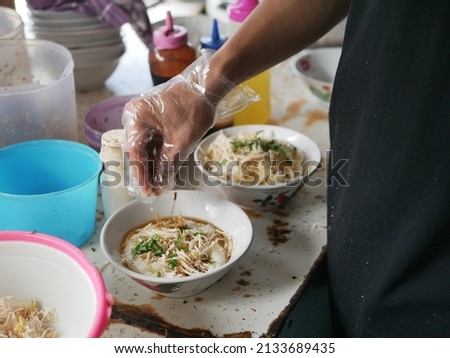 Chicken porridge seller or tukang bubur ayam is prepares his meal for customers or pelanggan. Bubur Ayam (Chicken Porridge), Malaysian Traditional Food Consist of White rice porridge with salted egg,  Royalty-Free Stock Photo #2133689435