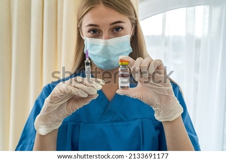 young beautiful blonde nurse in a mask and gloves holding a vaccine and a syringe in her hands. Medicine concept. Vaccination concept Royalty-Free Stock Photo #2133691177