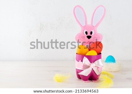 Craft hare with painted Easter eggs on a wooden table. Horizontal orientation, copy space.