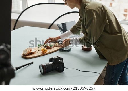 Cropped shot of female food photographer setting up gourmet bruschetta with props in studio, copy space