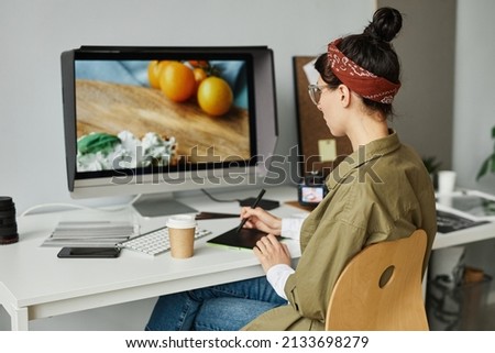 Portrait of young female photographer editing pictures at workplace in studio using pen tablet, copy space
