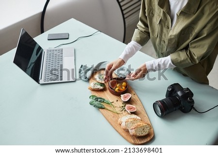 High angle view at female food photographer arranging gourmet dish with props while working in studio, copy space