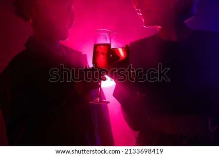 Backlit portrait of two young women enjoying drink while partying in smoky club with neon lights, copy space Royalty-Free Stock Photo #2133698419