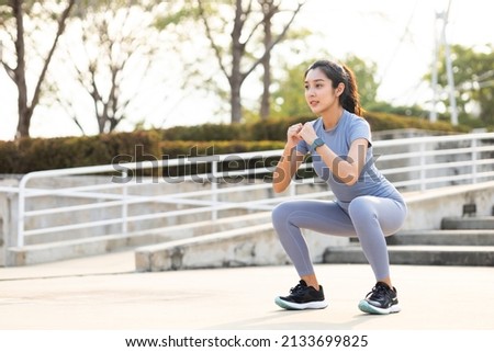 Beautiful fitness asian woman doing squat sit up exercise workout at sport stadium. Attractive female warming up body training wearing sportswear. Healthy and active lifestyle concept. Royalty-Free Stock Photo #2133699825