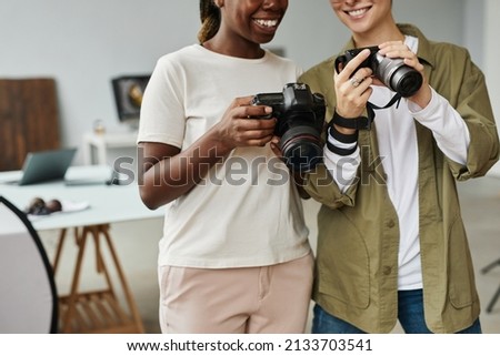 Cropped shot of two smiling female photographers holding cameras while working in photo studio, copy space
