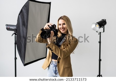 portrait of woman taking photos using a professional camera in the studio with lighting on the background