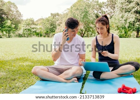 Happy Asian couple use their smartphone to make a phone call and enter their credit card number to order online from laptop shop after exercising and taking break Use an online hotspot for convenience Royalty-Free Stock Photo #2133713839