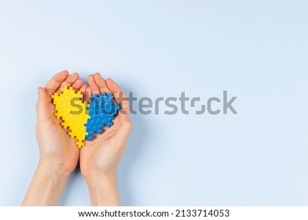 World Down syndrome day background. Hands holding blue and yellow Down syndrome awareness day heart on light blue background. Top view, copy space Royalty-Free Stock Photo #2133714053