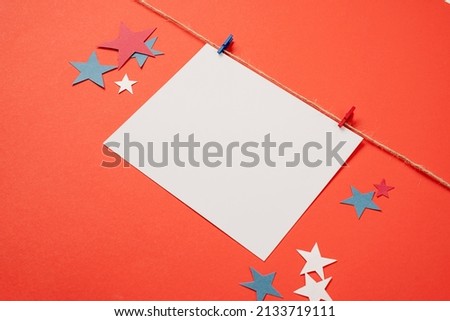 USA Memorial day, Presidents day, Veterans day, Labor day, or 4th of July celebration. Blank white paper for mockup design with red and blue clips on craft rope, red background