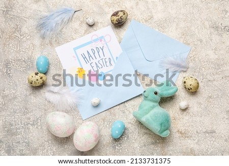 Beautiful Easter composition with greeting card, painted eggs and bunny on grey background