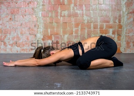 Caucasian blonde yoga woman in black clothes practicing sport pose extended puppy indoor Royalty-Free Stock Photo #2133743971