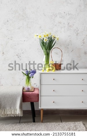 Bench and chest of drawers with Easter decor near light wall in room