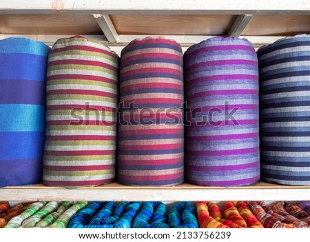 The handmade woven silk rolls are on shelves inside a local clothing store in Thailand, front view with the copy space.