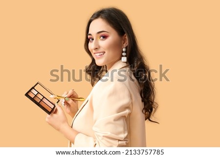 Woman with creative makeup holding decorative cosmetics and brush on color background. International Women's Day Royalty-Free Stock Photo #2133757785